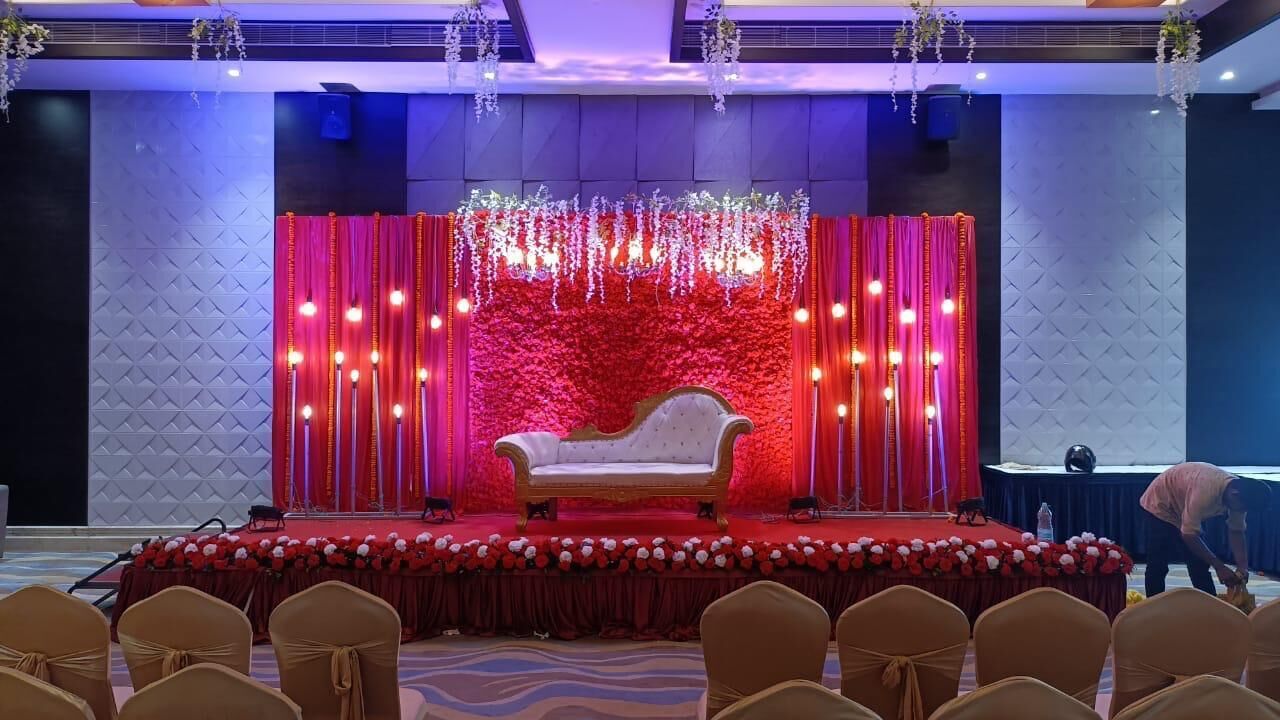 Un palco con un divano bianco, tende rosse e decorazioni floreali.