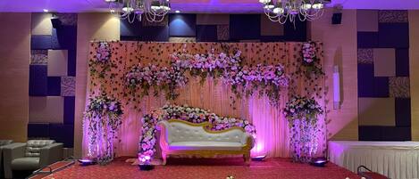A stage with a sofa, floral arrangements, and chandeliers.