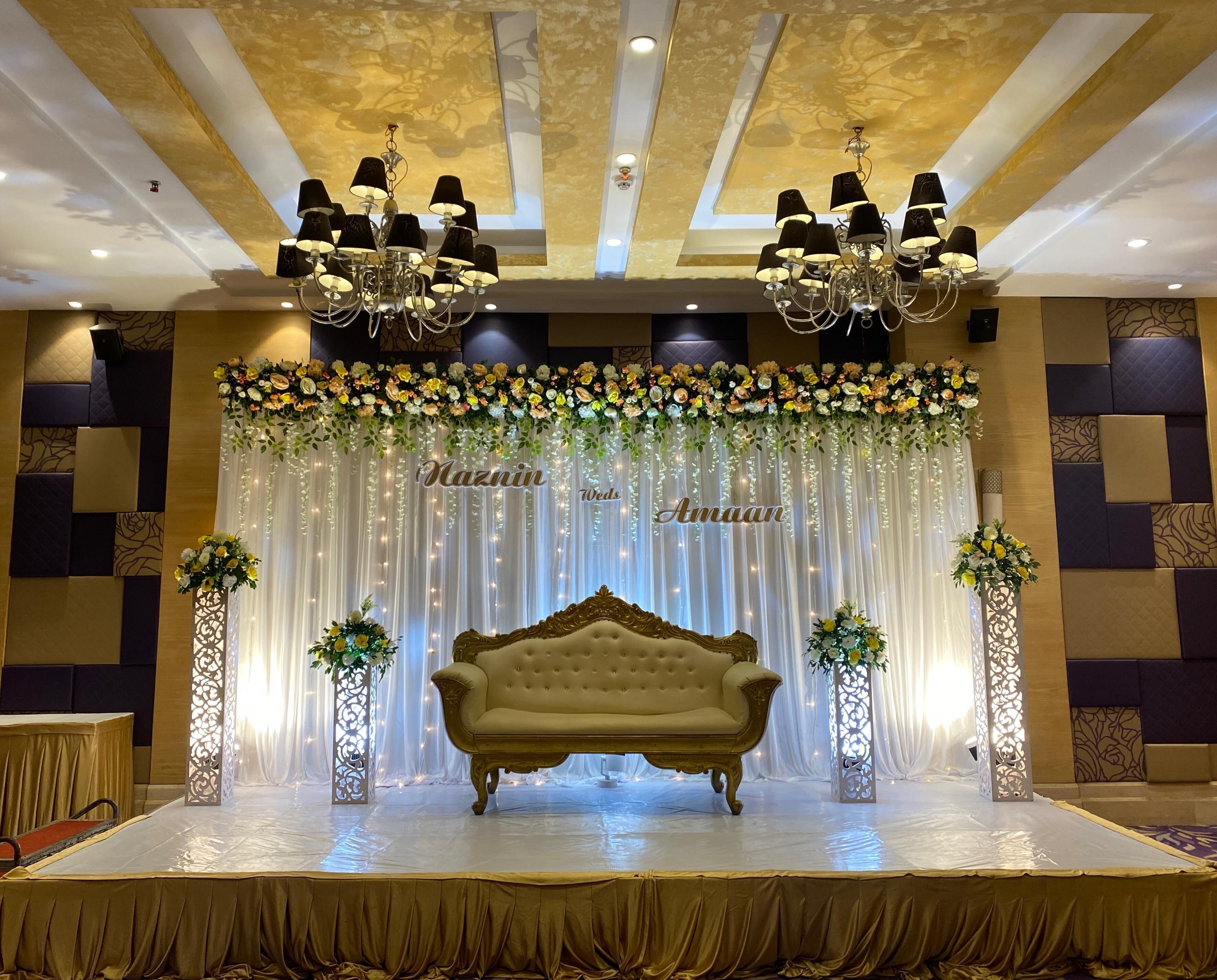 Une scène avec un canapé doré, des décorations florales et des lustres.