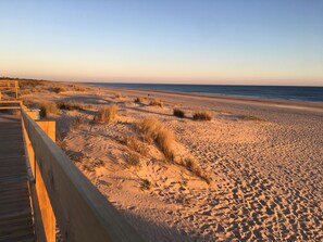 A sandy beach with a wooden boardwalk.