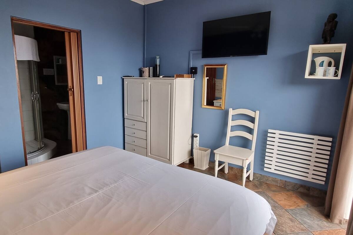 Ein Schlafzimmer mit Bett, Kleiderschrank, Sessel, Fernseher und Heizkörper.
