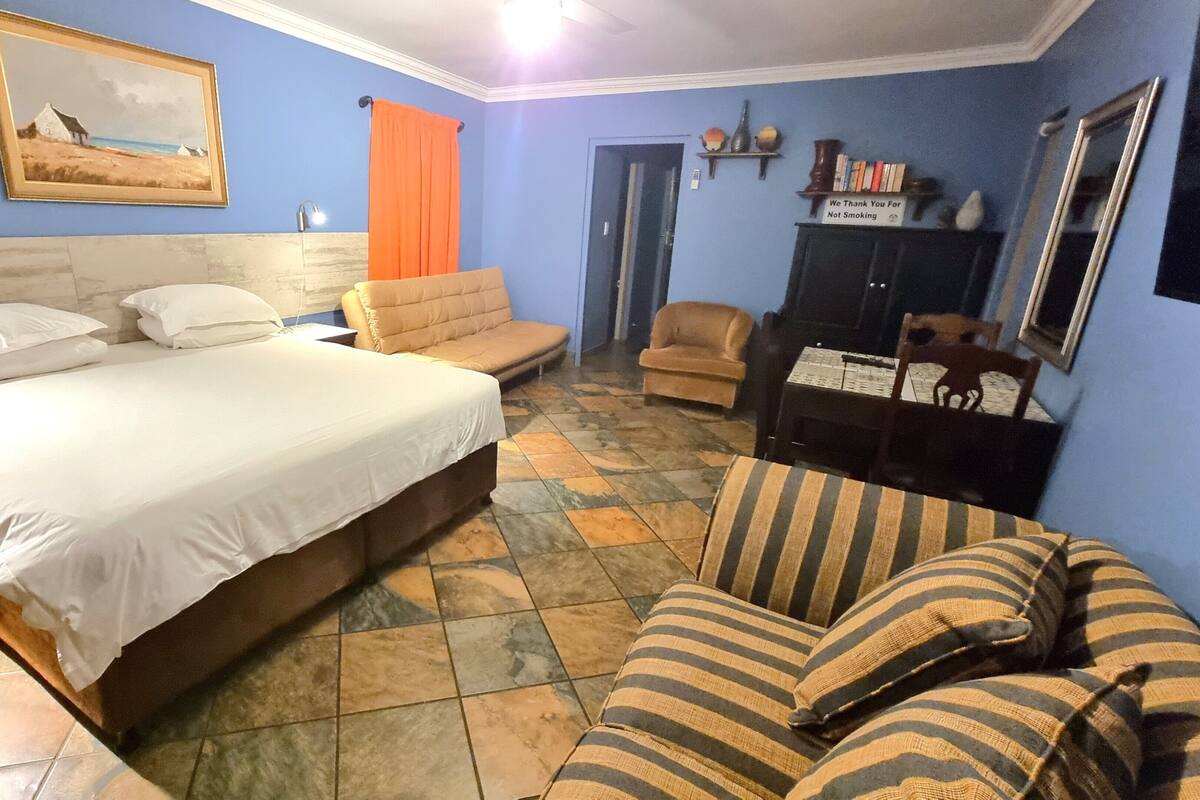 Ein Schlafzimmer mit einem Bett, einem Schlafsofa, einem Sessel, einem kleinen Tisch und einem Schrank.