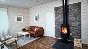 Un salon chaleureux avec un canapé marron, une table basse blanche et une cheminée à la façade en pierre.