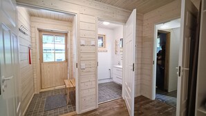 Un intérieur en bois avec un banc, une porte donnant accès à une salle de bain et une fenêtre offrant une vue.