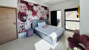 A modern bedroom with a large bed, a nightstand, a wall-mounted lamp, and a view of the outdoors through a large window. - The Premier Studio (Constanta)