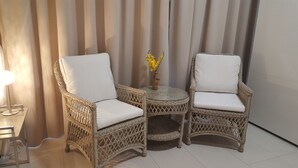 Two wicker chairs with white cushions, a small round table, and a vase with yellow flowers. - The Premier Studio (Constanta)