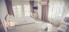 Quarto de hotel moderno com uma cama grande, uma escrivaninha, uma cadeira, uma mesa redonda e uma televisão.