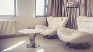 Una sala de estar moderna con dos sillones de cuero, una mesa redonda y una lámpara de pie.