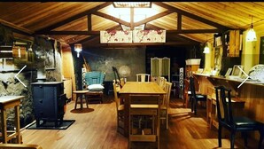 Un interior rústico de madera con una mesa de comedor central, sillas, una pequeña zona de cocina y una barra.