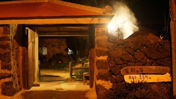 Un edificio de piedra con una puerta de madera y un letrero en coreano.