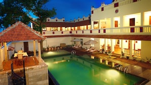 A hotel with a pool, outdoor seating, and multiple balconies. - Chidambara Vilas - A Luxury Heritage Resort (Thirumayam)