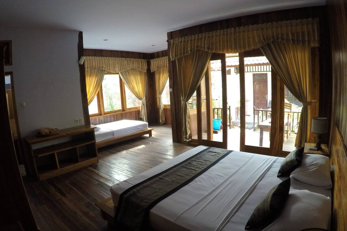 Une chambre avec un grand lit, un banc et une vue sur l’extérieur.