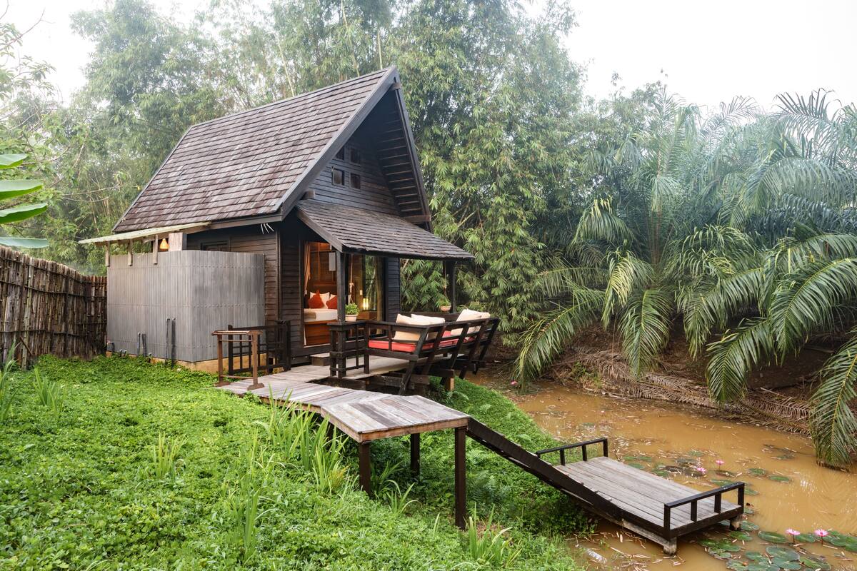 A wooden cabin with a sloped roof, a porch with seating, and a small wooden table.