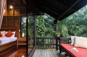 Um quarto de madeira com uma cama, uma mesinha de cabeceira e um sofá vermelho.
