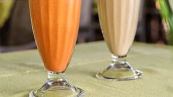 Two tall glasses of iced drinks with straws, placed on a table with a green cloth.