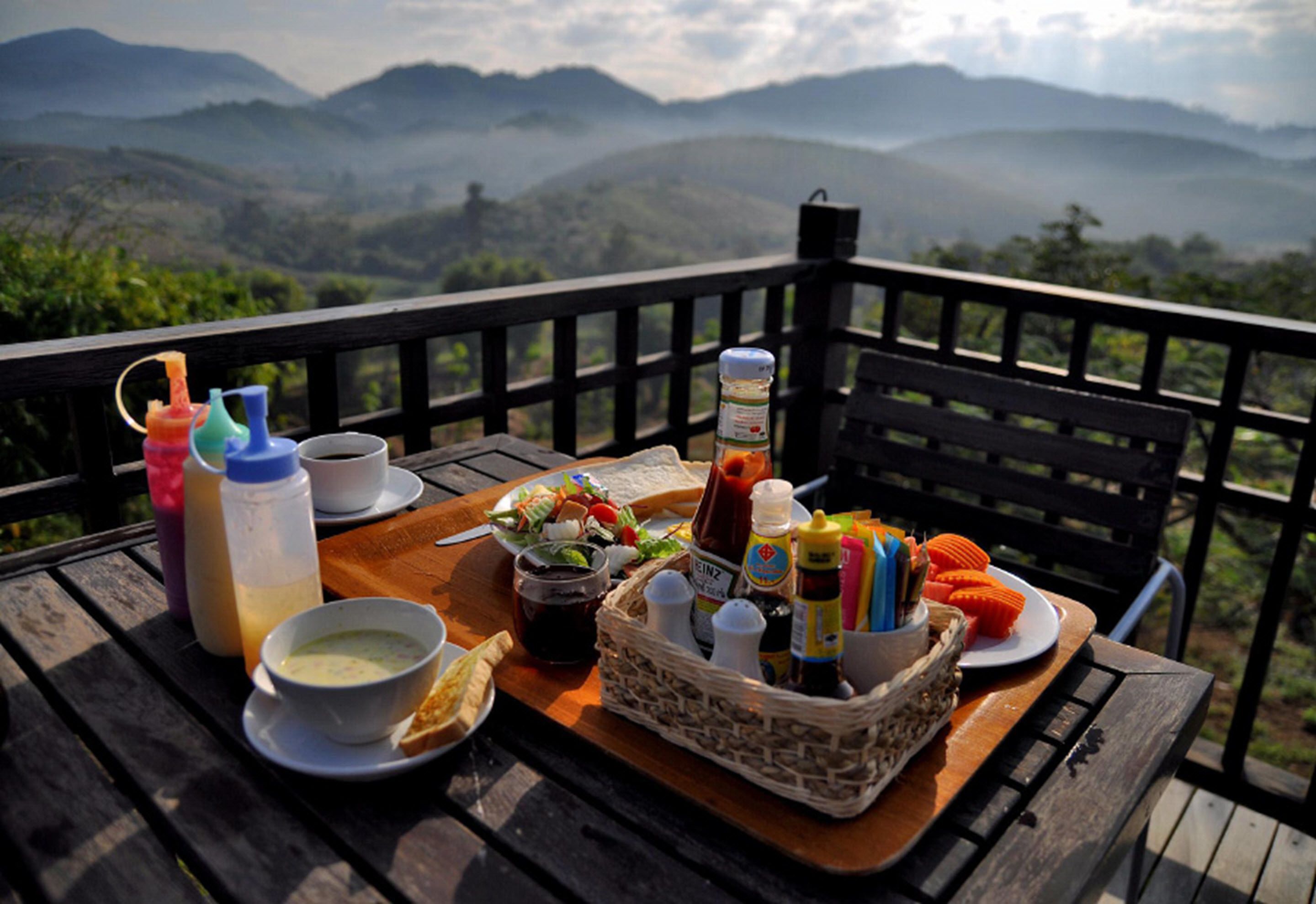 A picnic setup on a wooden deck with a scenic mountain view in the background.