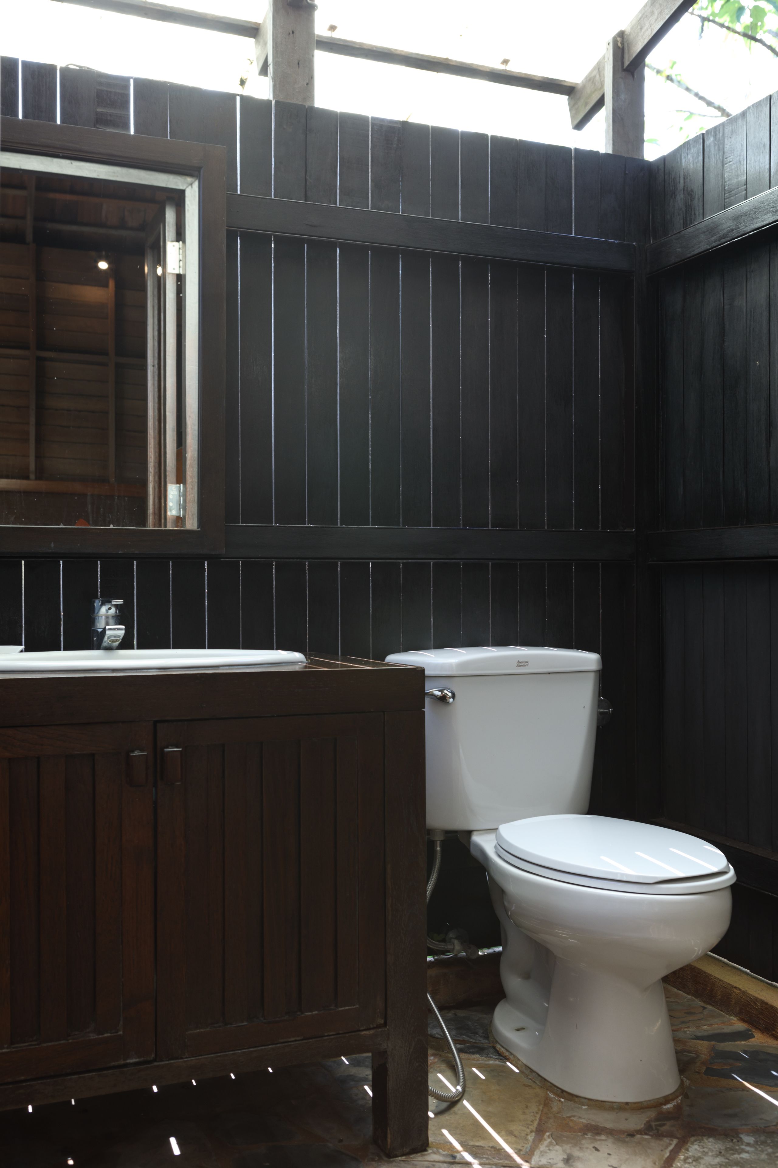 Ein Badezimmer mit einem Holzwaschtisch, einer weißen Toilette und einem gefliesten Boden.