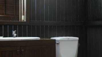 Ein Badezimmer mit einem Holzwaschtisch, einer weißen Toilette und einem gefliesten Boden.