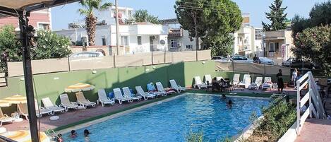 Een buitenzwembad, parasols bij het zwembad en ligstoelen