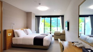 Una habitación de hotel con cama, mesita de noche, silla y un espejo grande.