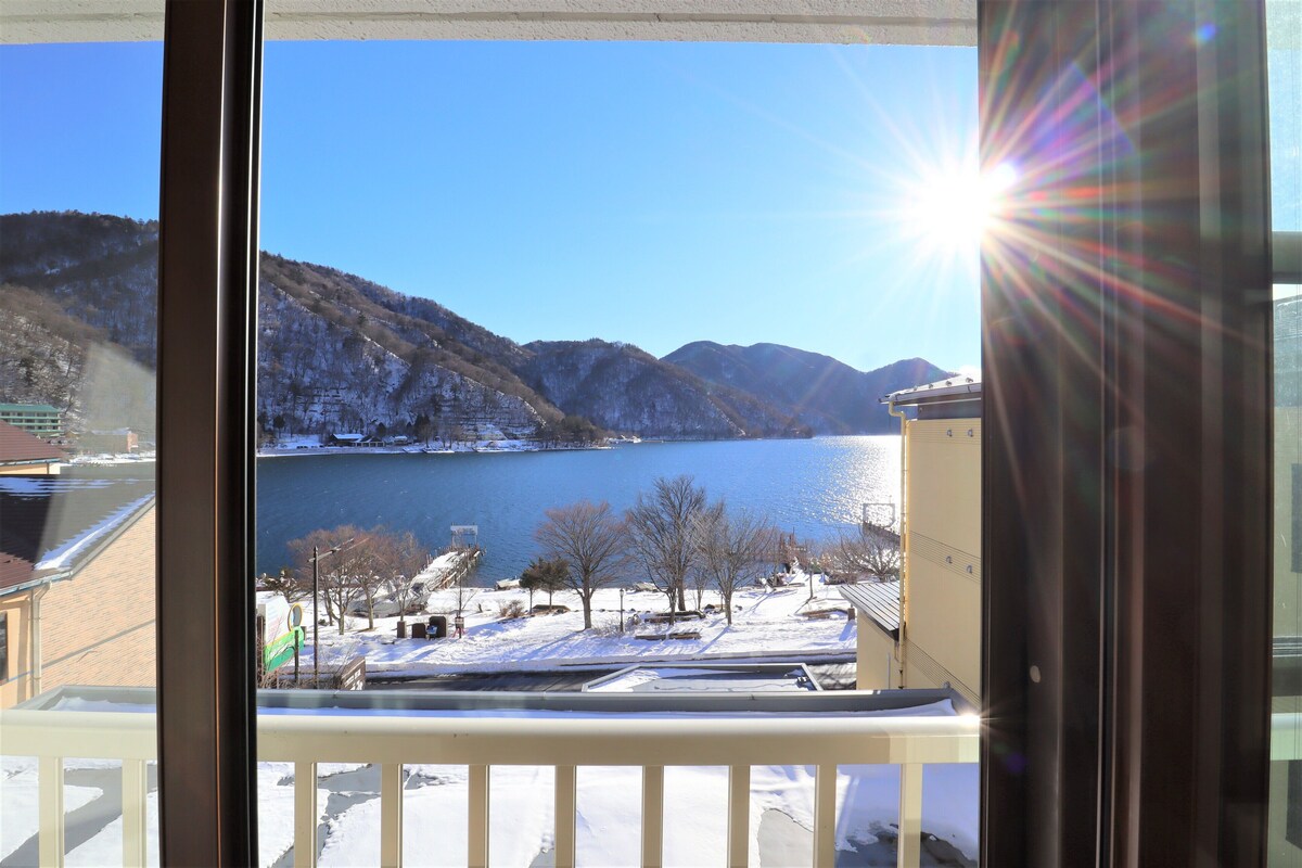 A view from a balcony overlooking a lake with mountains in the background.