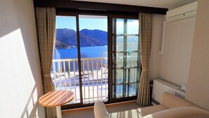 Un balcón con vistas a un lago y montañas, un sofá, una mesita y cortinas.