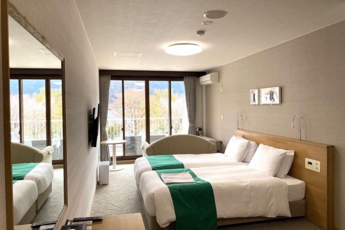 Une chambre d’hôtel avec deux lits, une télévision, un bureau et une vue sur un paysage montagneux.