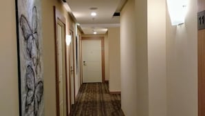 Un pasillo de hotel con una alfombra estampada, una obra de arte con mariposas en la pared izquierda y una puerta con el número 11.