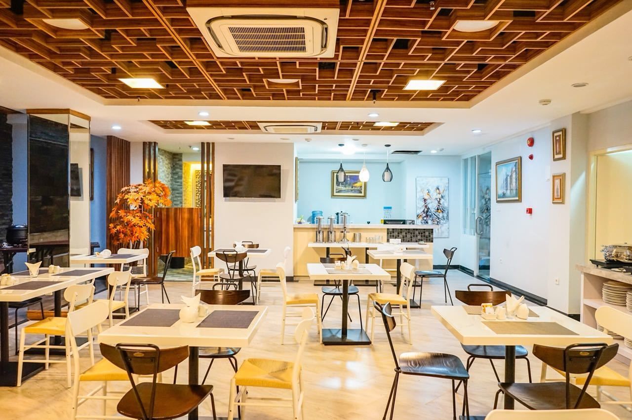 Un comedor moderno con paneles de techo de madera, mesas blancas y sillas negras.