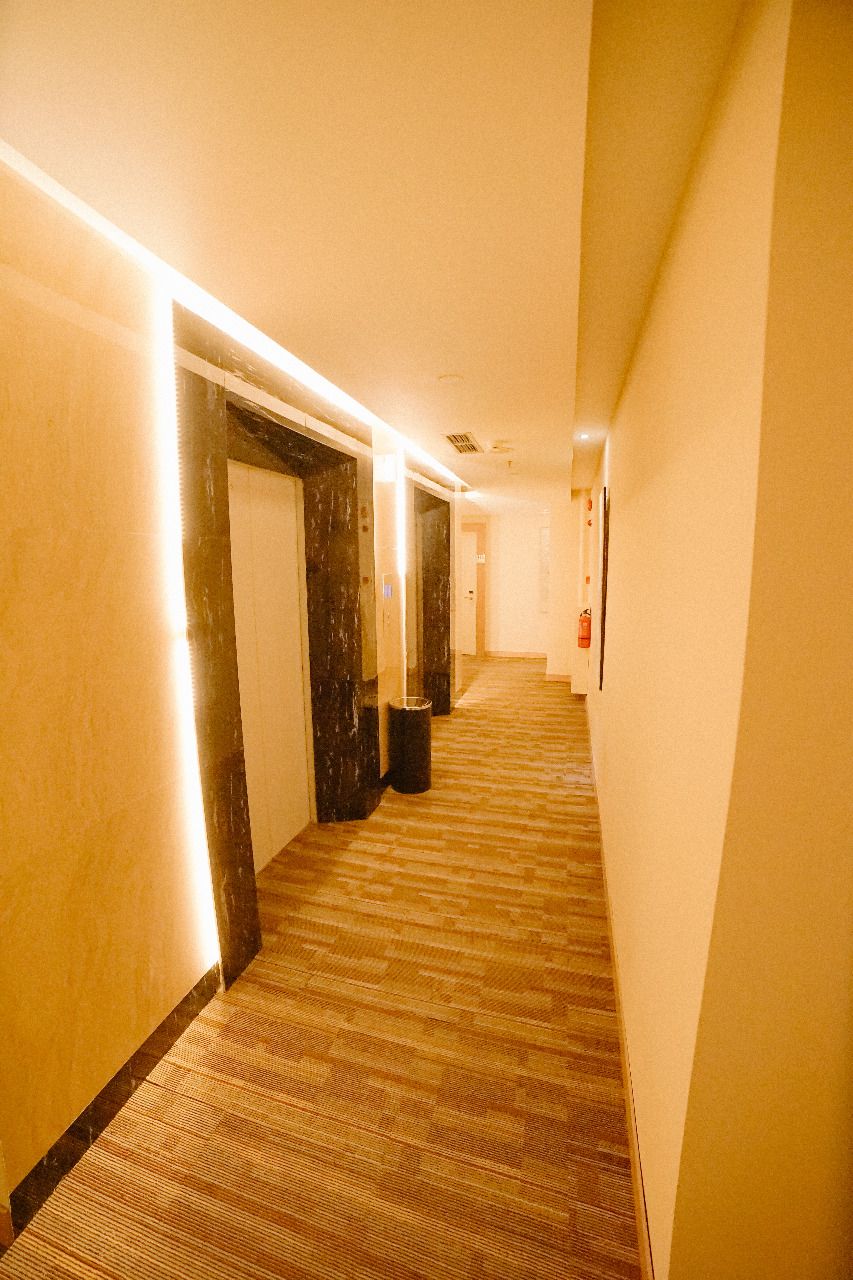 A hotel hallway with carpeted floors, doors, and a trash bin.