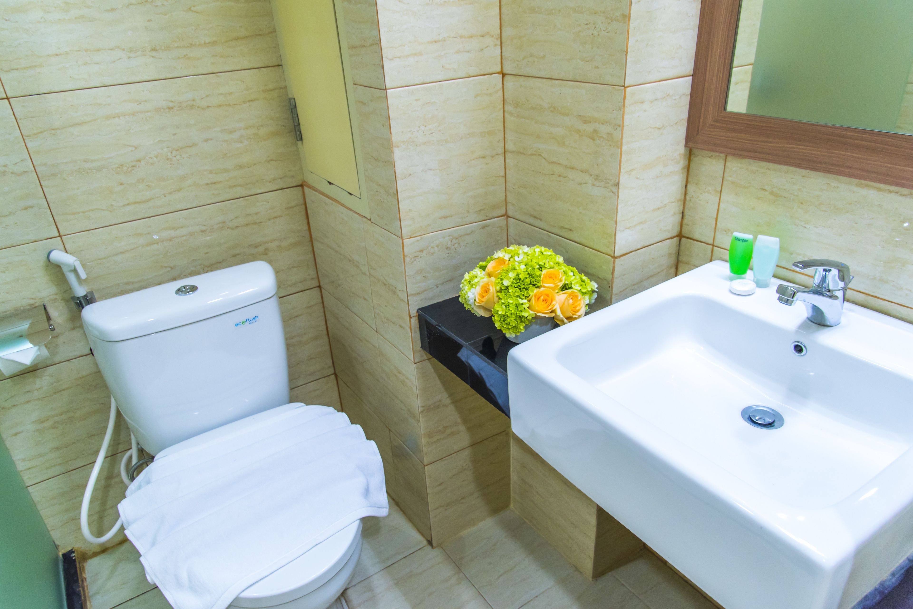 A bathroom with a toilet, sink, and a bouquet of flowers on the counter.