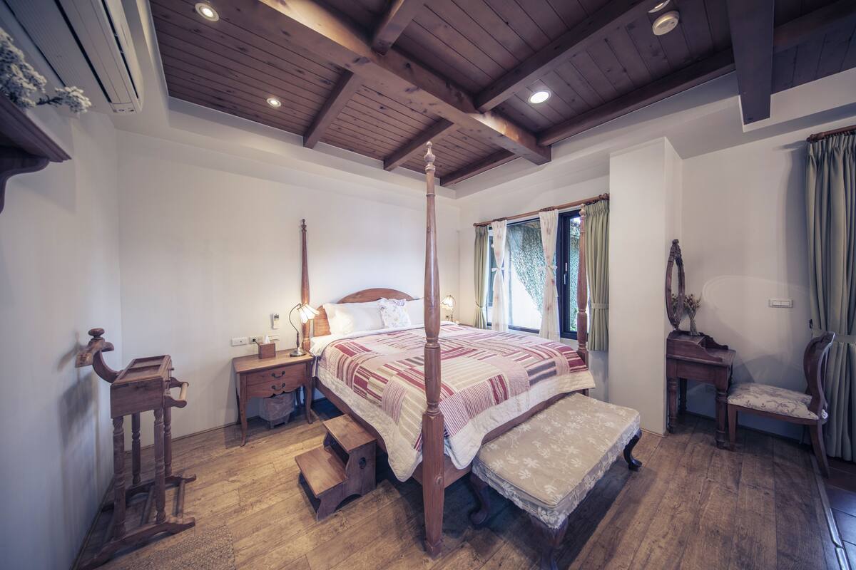 Un dormitorio tradicional con cama con dosel, suelo de madera y techo de madera.