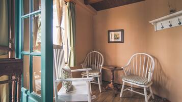 A room with wooden flooring, white rocking chairs, a small table, and a teal door.