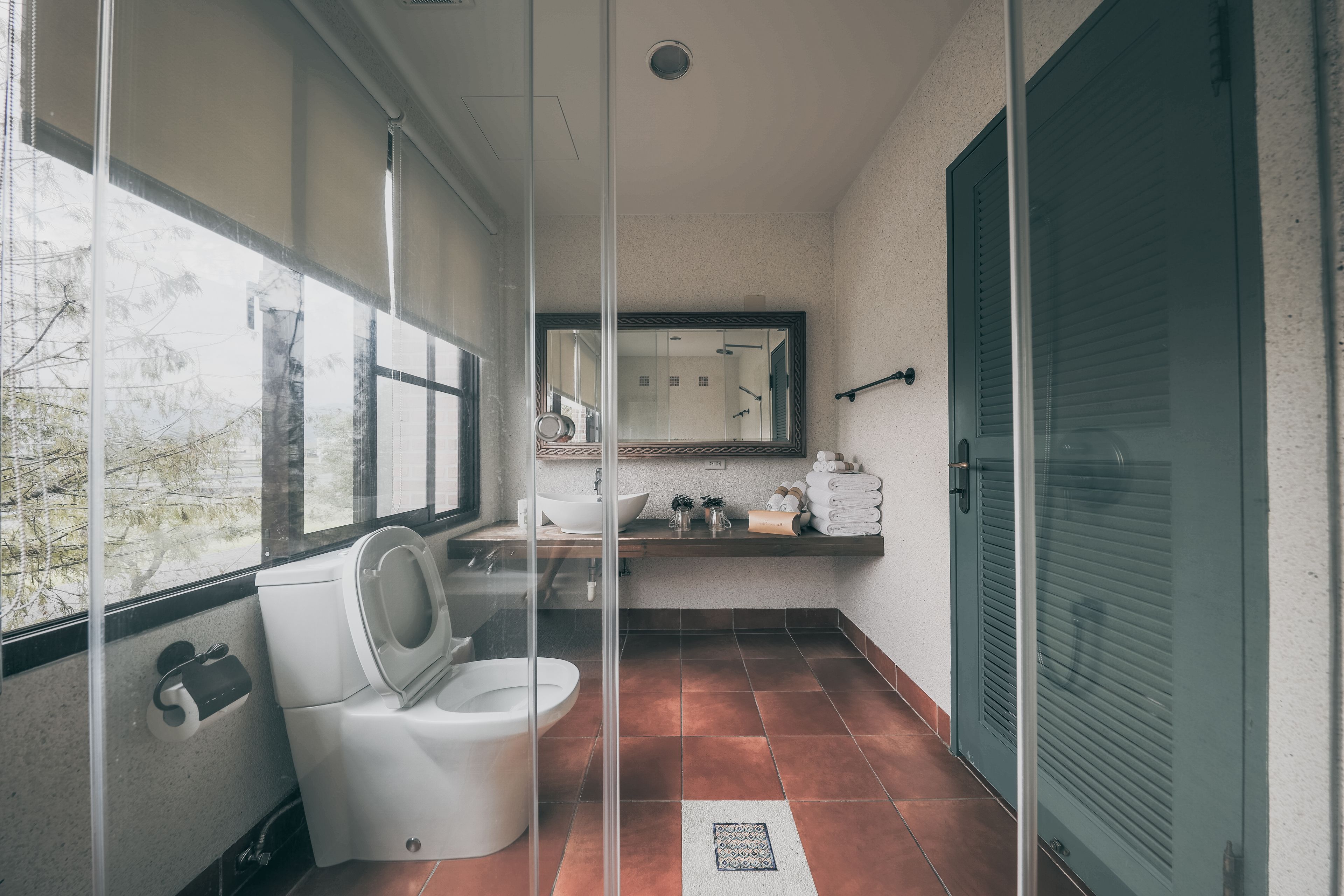 A bathroom with a toilet, sink, and large window.