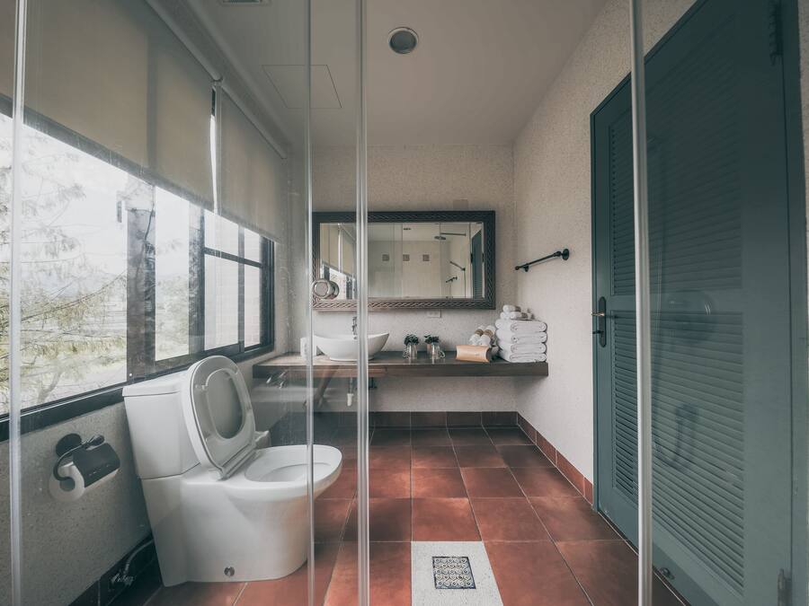 A bathroom with a toilet, sink, and large window.