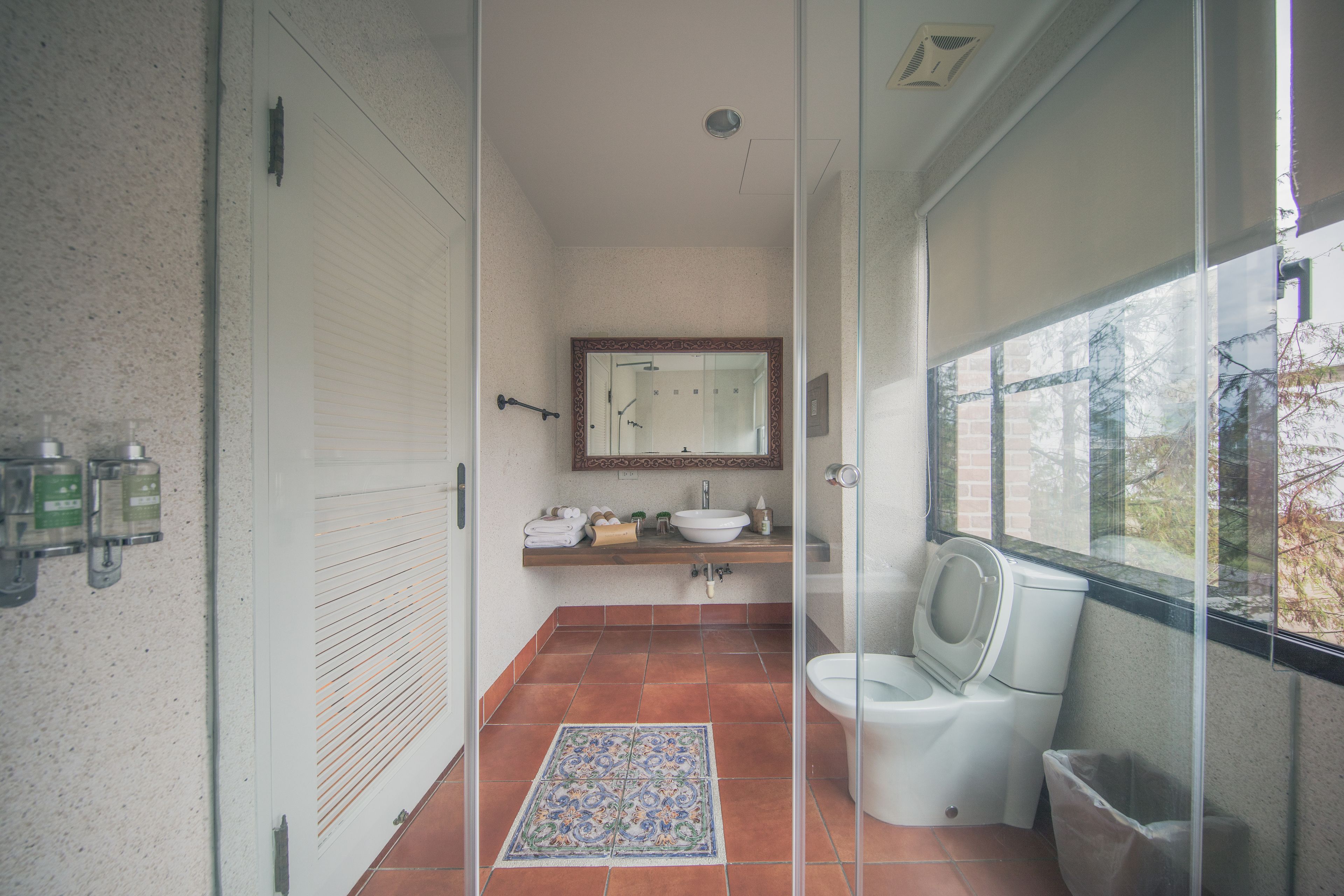 A compact bathroom with a glass shower enclosure, a white toilet, and a sink with a mirror above it.