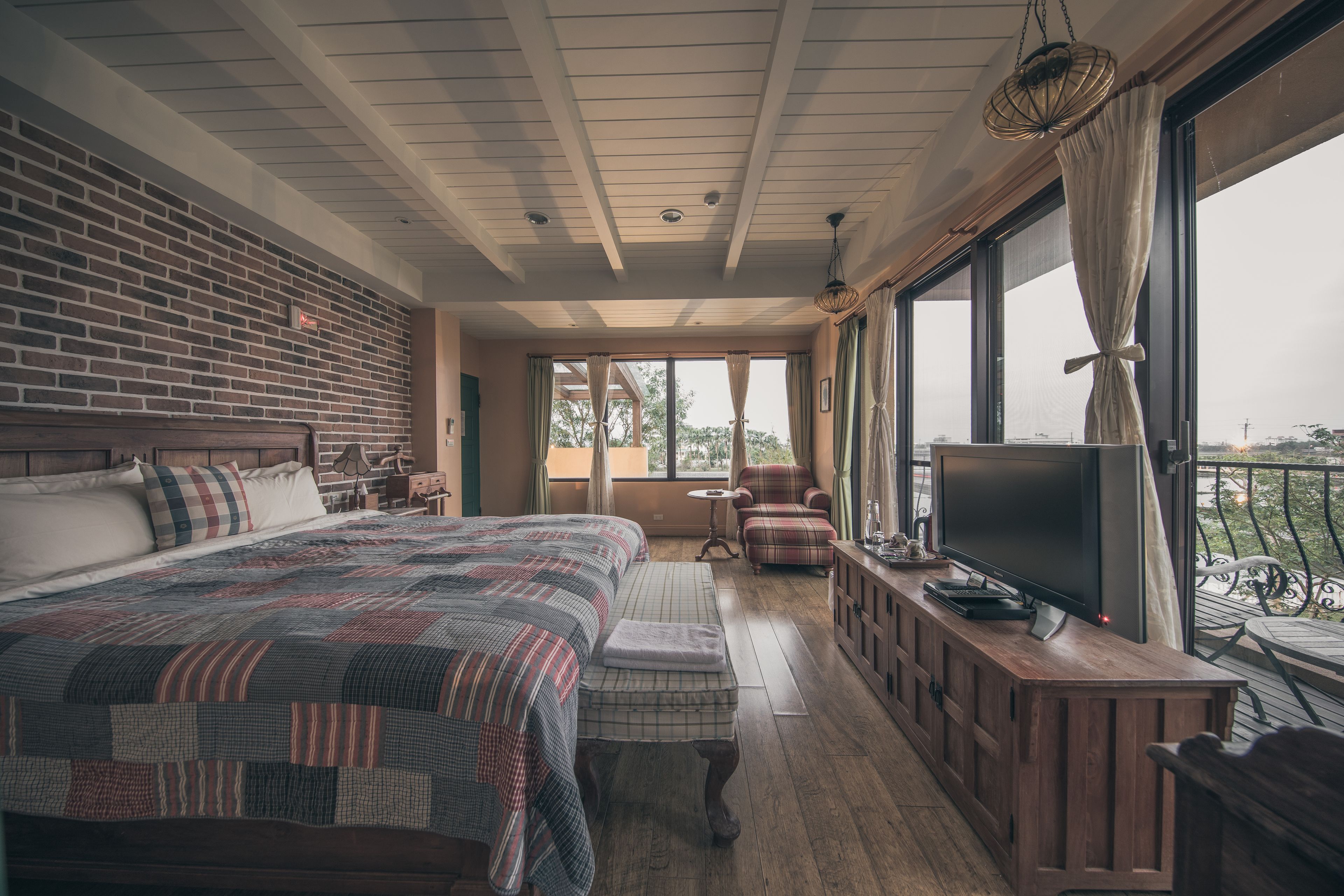 Un dormitorio amplio con una cama grande, televisor y balcón con vistas.