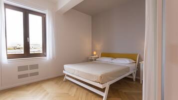 A bedroom with a bed, a nightstand, a window, and a heater.
