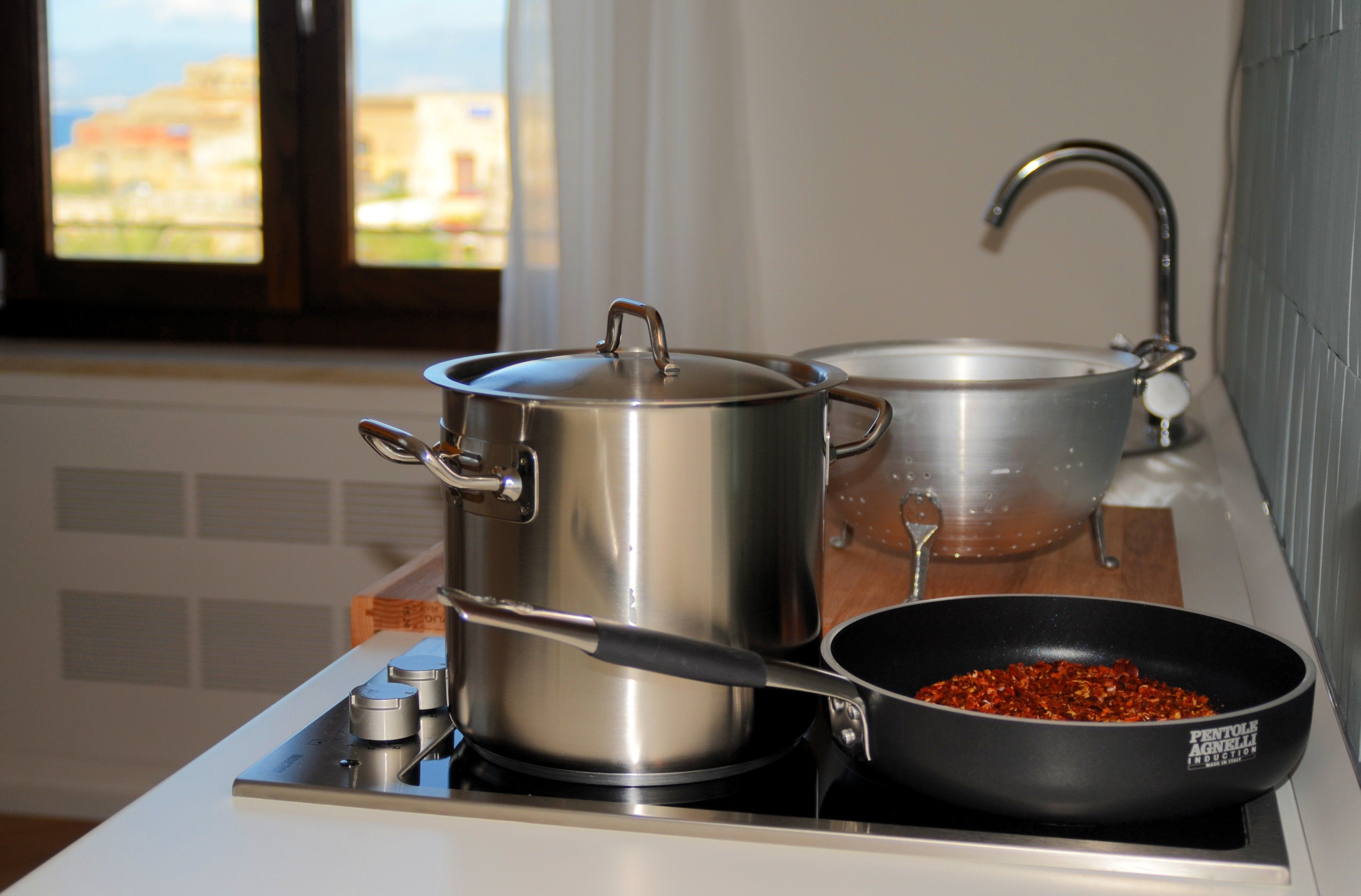 Een keuken met roestvrijstalen pannen en een zwarte koekenpan op een fornuis.