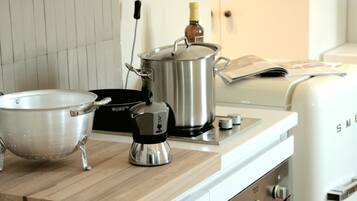 Een keuken met een roestvrijstalen pan, een vergiet en een koffiezetapparaat op een houten aanrecht.