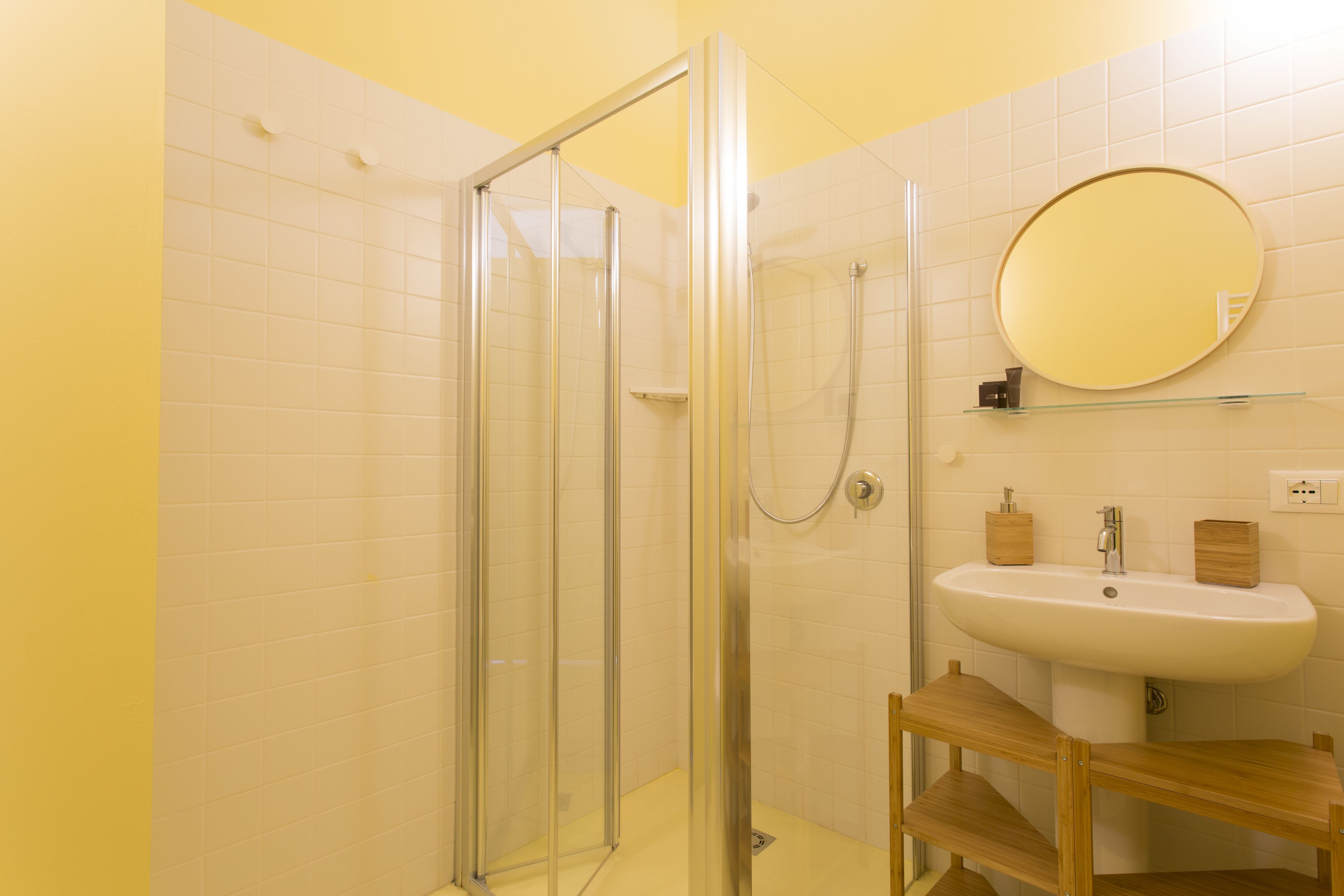 Un baño con ducha de mampara, lavabo y espejo.
