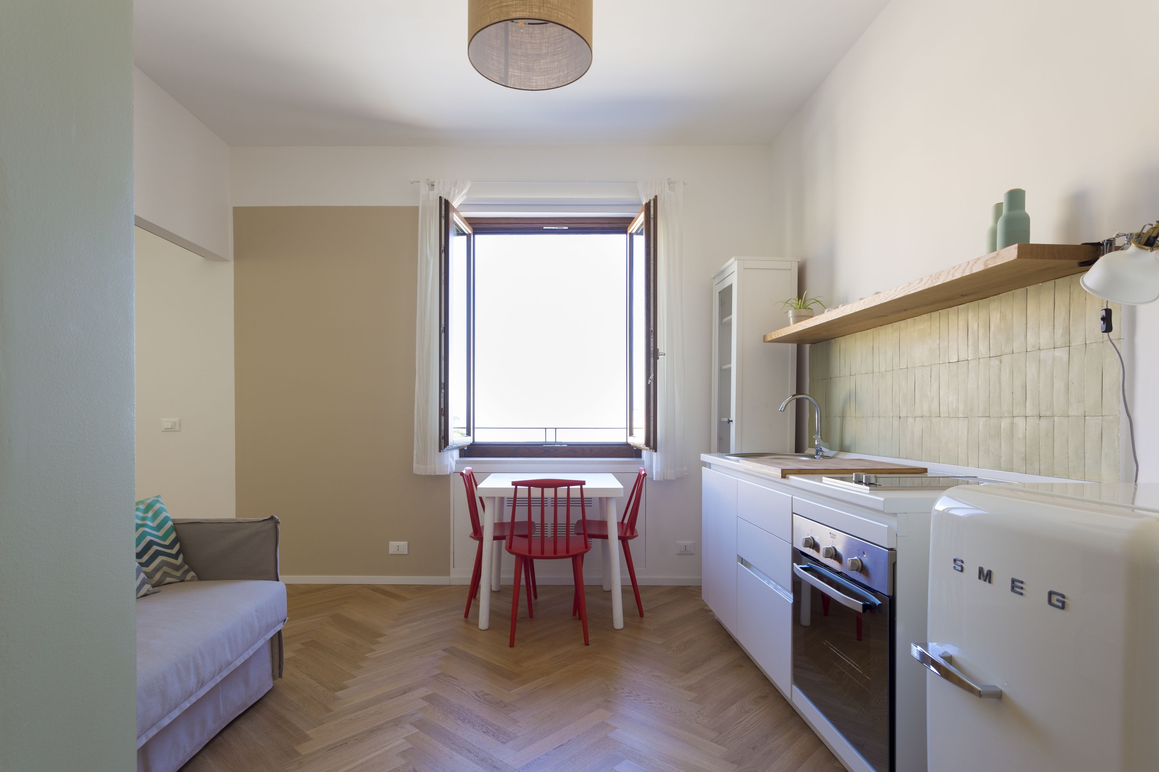 Eine kleine Küche mit einem weißen Kühlschrank, einer Holz Arbeitsplatte und einem Fenster mit Vorhängen.