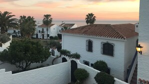 A coastal village with white buildings and terracotta roofs, palm trees, and a sunset view. - El Capistrano, Nerja 2 bedroom apartment with south facing private garden (Nerja (Malaga))