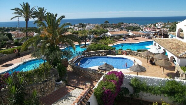 A resort with multiple swimming pools, palm trees, and a view of the sea. - El Capistrano, Nerja 2 bedroom apartment with south facing private garden (Nerja (Malaga))