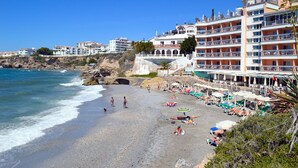 A beach with a hotel in the background. - El Capistrano, Nerja 2 bedroom apartment with south facing private garden (Nerja (Malaga))