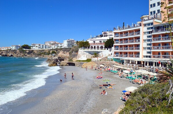 A beach with a hotel in the background.
