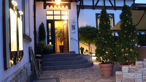 Una entrada de edificio con una escalera que lleva a una puerta, un árbol de Navidad y un camino de ladrillo.