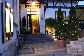 A building entrance with a staircase leading up to a door, a Christmas tree, and a brick pathway. - Gasthof und Pension Frankenthal (Gera)
