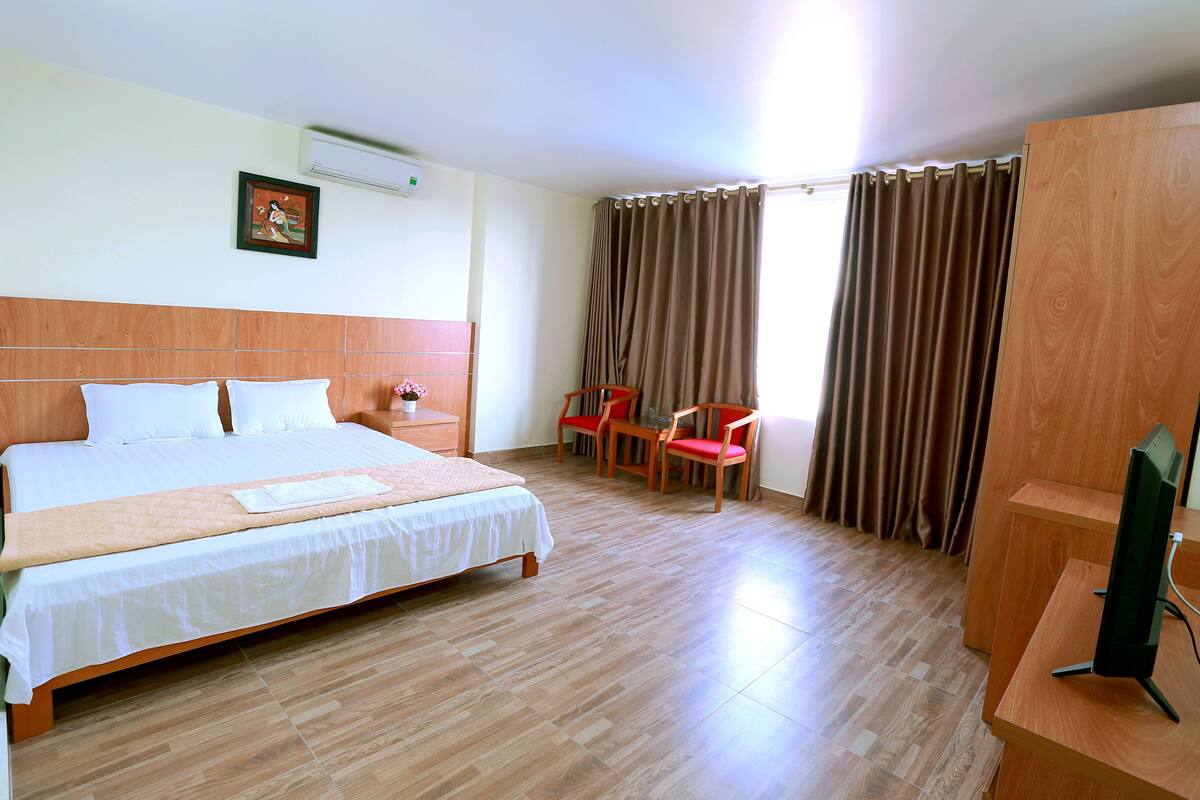 A hotel room with a large bed, a desk with a computer, a chair, and a TV.