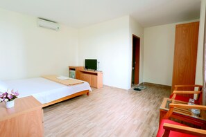 Una habitación con una cama, un escritorio con computadora, una silla y un armario.